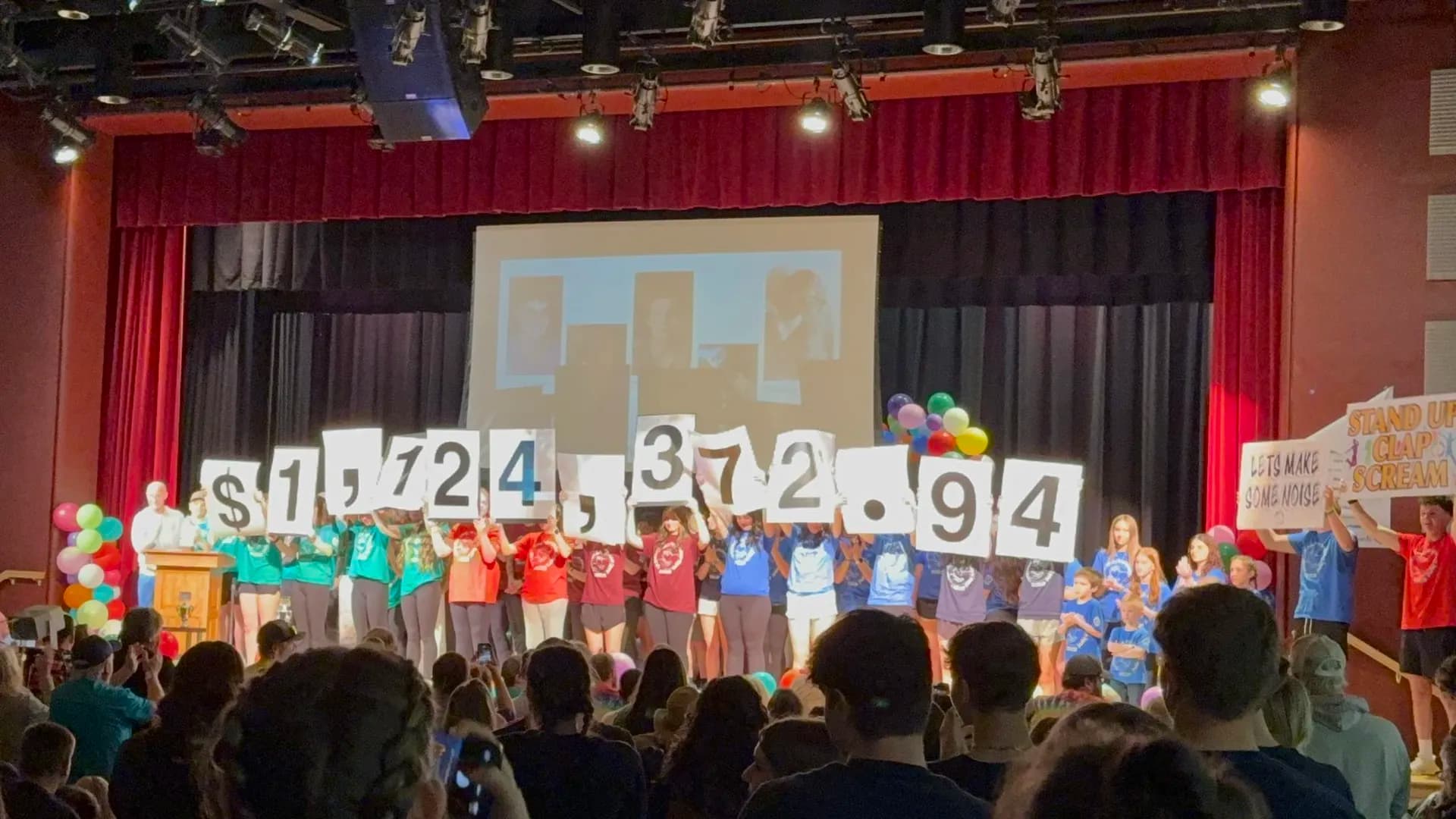 CHAMP students revealing the $1,124,372.94 fundraising total on stage